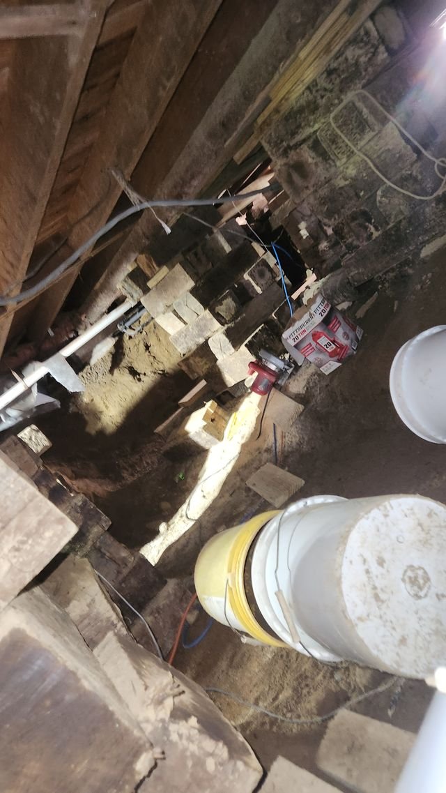 Looking down into the dig beside the cribbing, with buckets and tools on the dirt