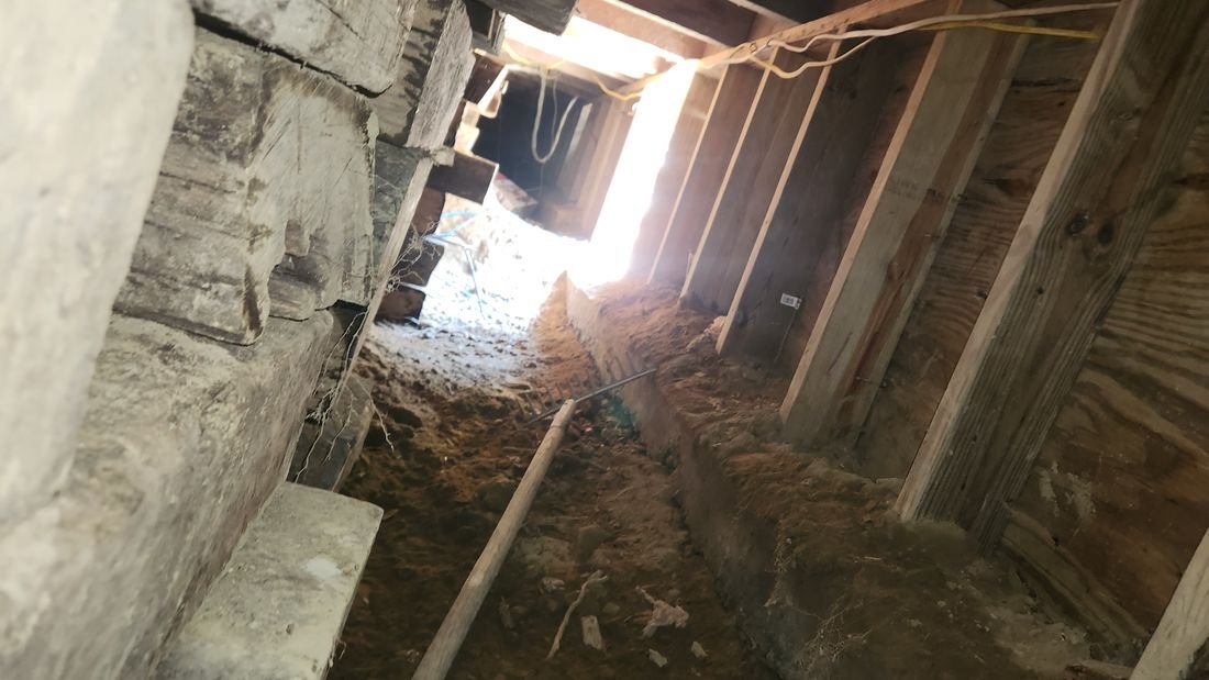 A trench dug along a framed wall, running toward daylight